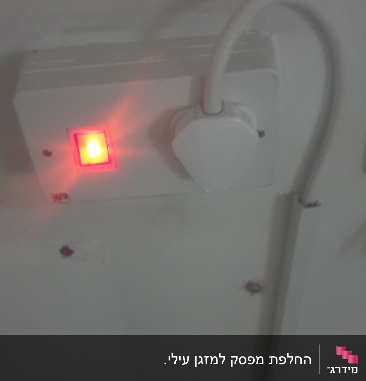 שקע חשמלי עם כבל מחובר ונורית אדומה דולקת